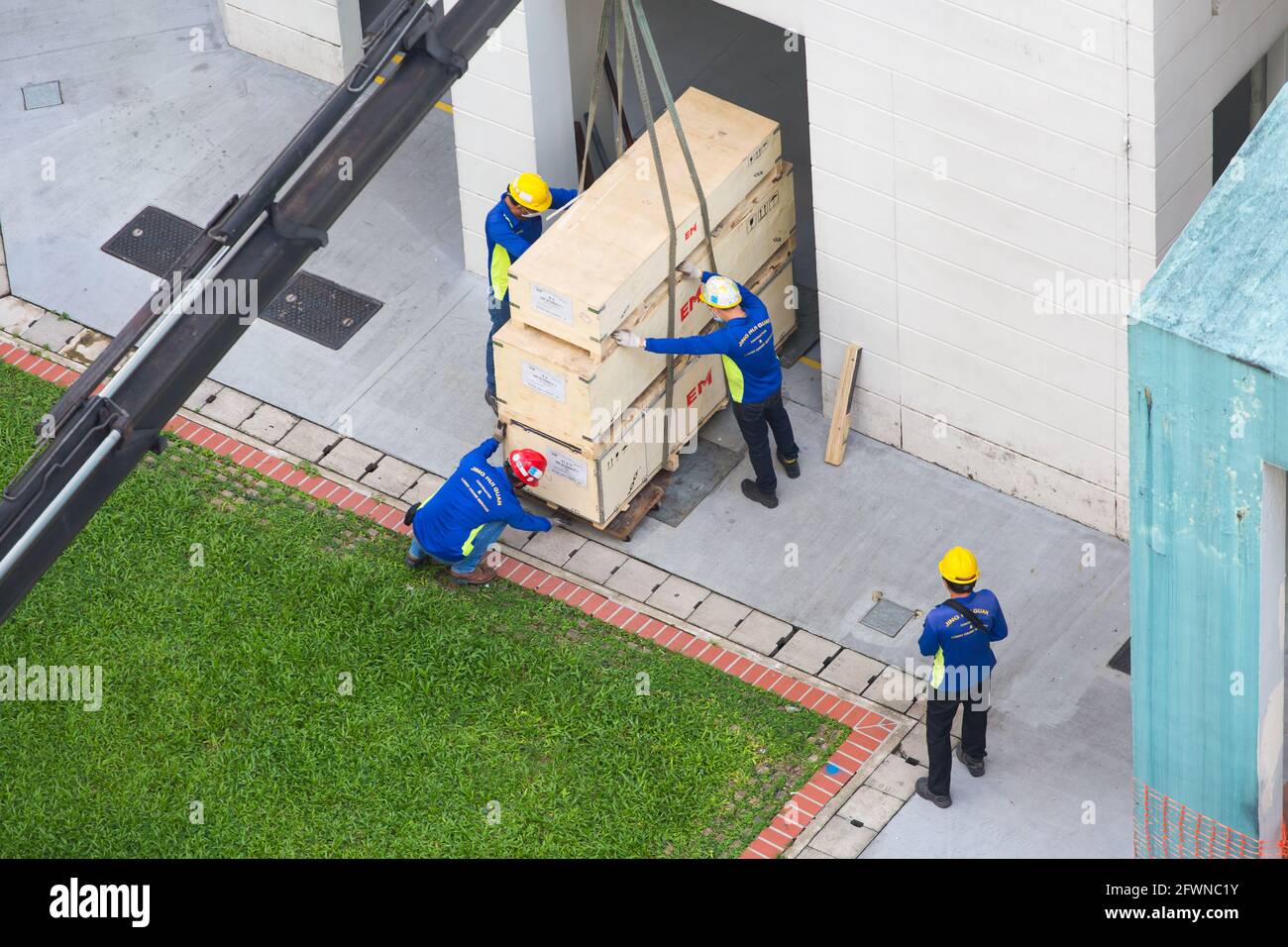 Vue aérienne des employés qui ajustent les caisses suspendues avant de les poser avec précaution. Banque D'Images