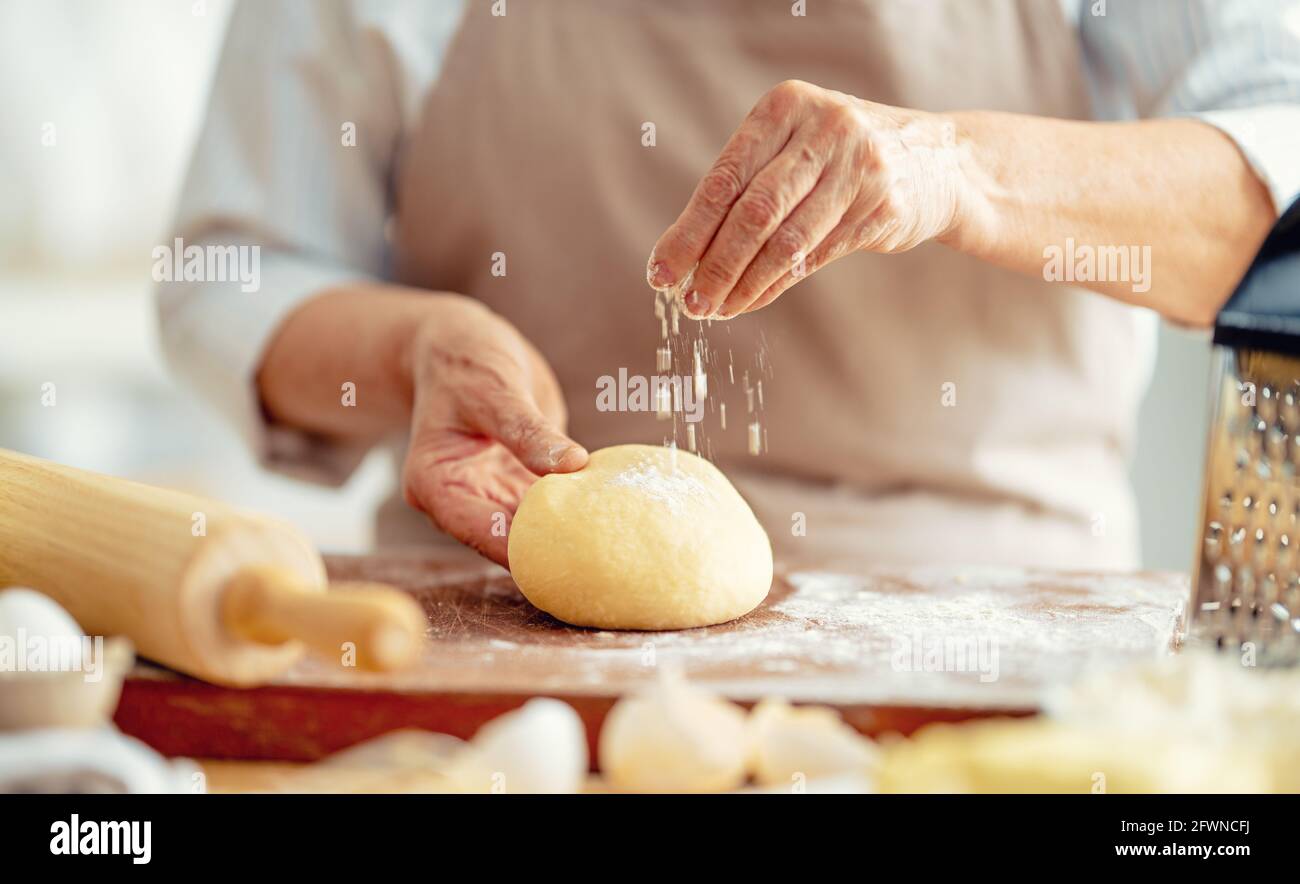 Vue rapprochée du boulanger en cours. Pain maison. Mains préparant la pâte sur une table en bois. Banque D'Images