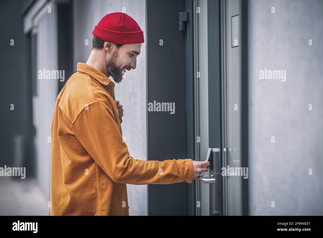 Jeune homme barbu ouvrant la porte avec une carte d'accès Banque D'Images