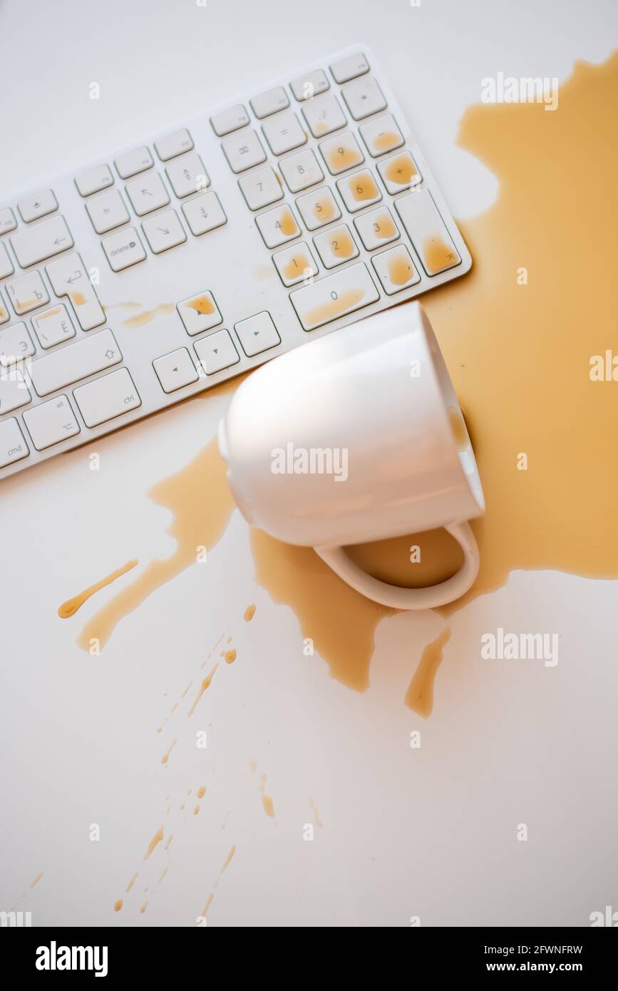 Café noir renversé sur un clavier d'ordinateur à un blanc tableau Banque D'Images Café noir renversé sur un clavier d'ordinateur à un blanc tableau Banque D'Images