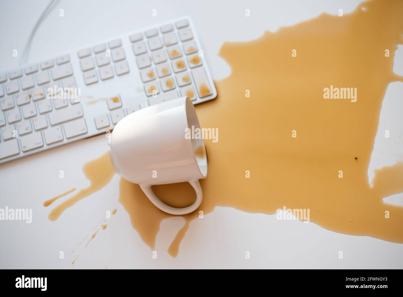 Café noir renversé sur un clavier d'ordinateur à un blanc tableau Banque D'Images Café noir renversé sur un clavier d'ordinateur à un blanc tableau Banque D'Images