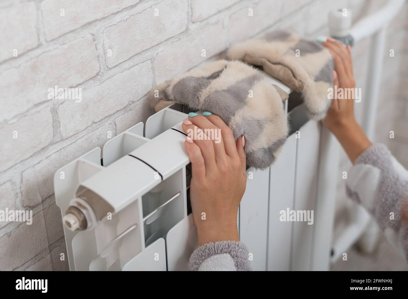 Une femme porte des moufles de fourrure sur un radiateur. Chauffage central  par temps froid d'hiver Photo Stock - Alamy