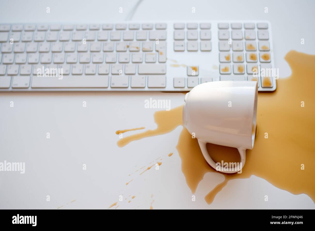 Café noir renversé sur un clavier d'ordinateur à un blanc tableau Banque D'Images Café noir renversé sur un clavier d'ordinateur à un blanc tableau Banque D'Images