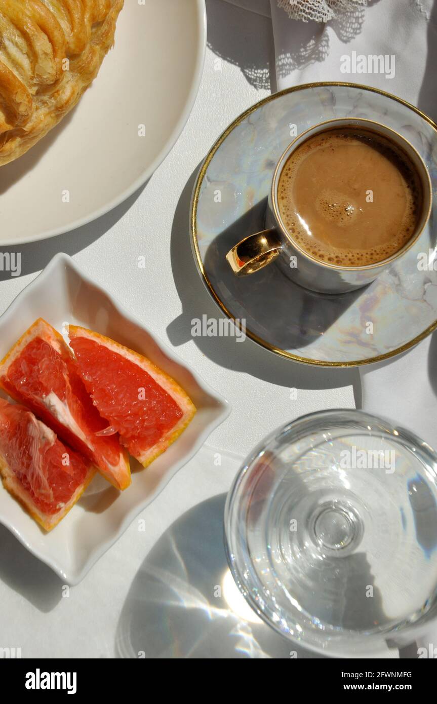 Plat de petit déjeuner avec café, pâtisserie, verre d'eau et pamplemousse Banque D'Images