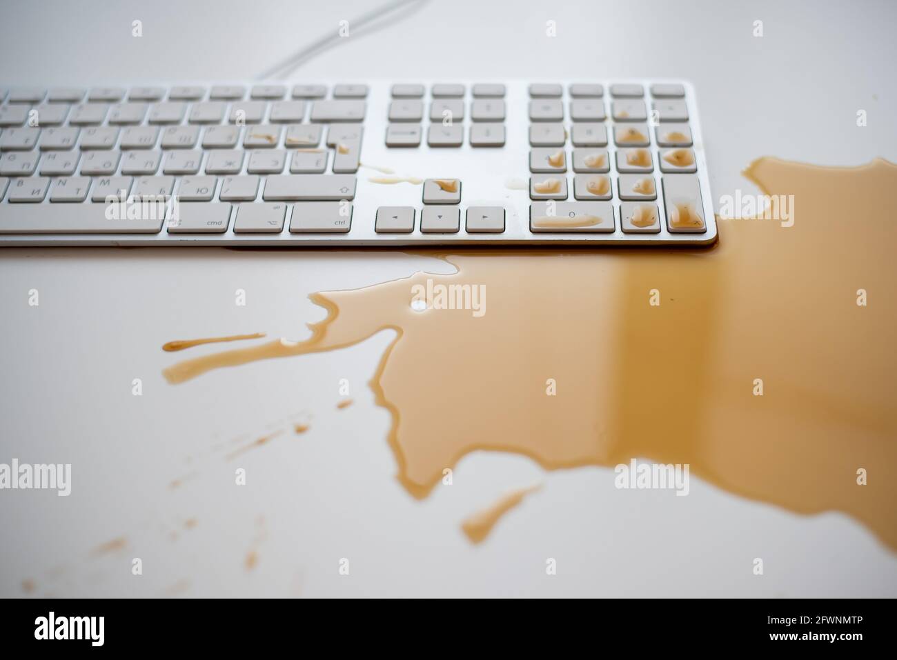 Projections de café noir sur un clavier d'ordinateur blanc Banque D'Images Projections de café noir sur un clavier d'ordinateur blanc Banque D'Images