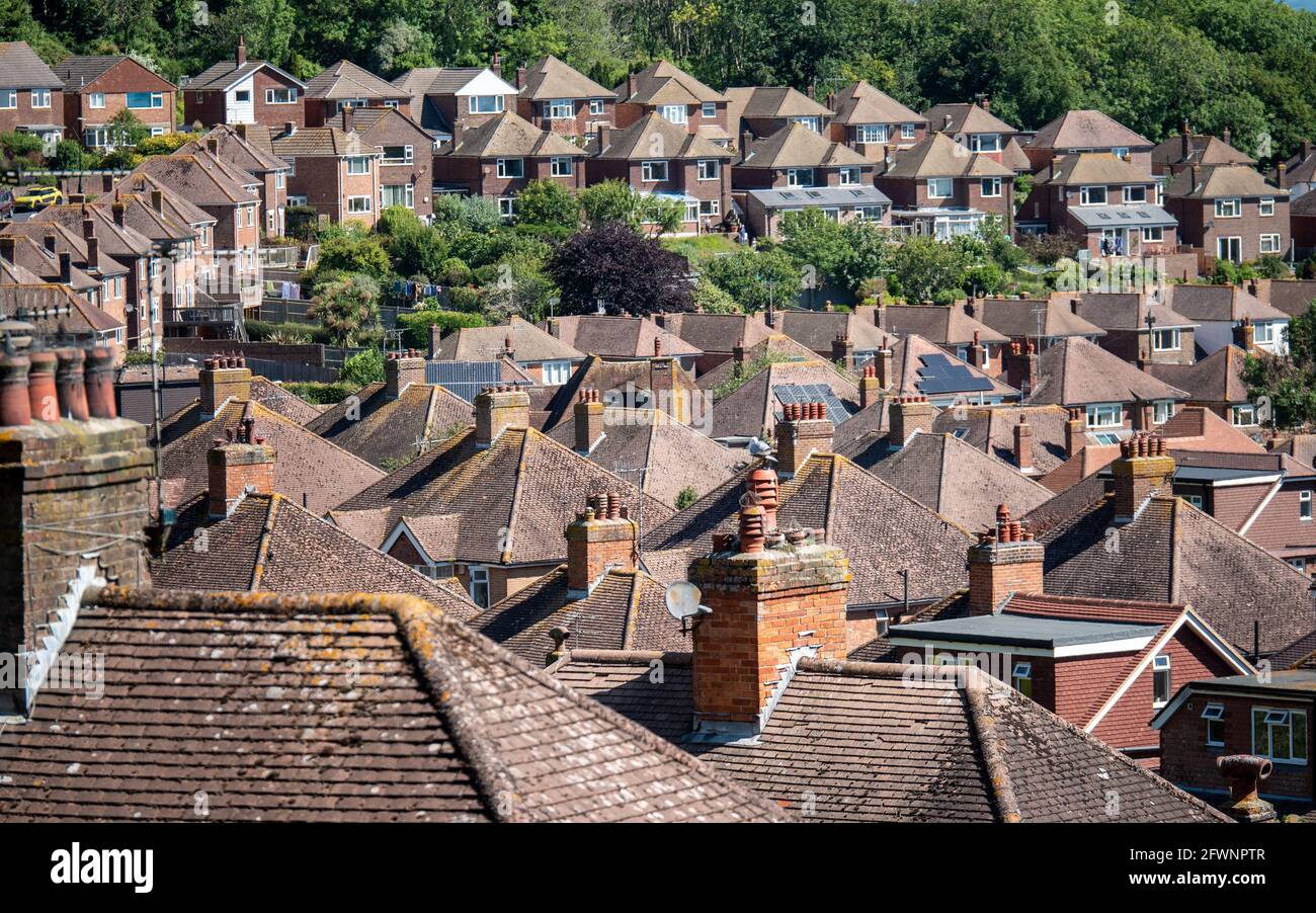 Toits de banlieue. Une vue en hauteur sur un domaine résidentiel de banlieue d'après-guerre des années 1950, en bordure de la vieille ville d'Eastbourne, adossée à des bois anciens. Banque D'Images