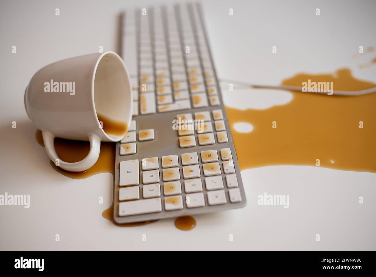 Café noir renversé sur un clavier d'ordinateur à un blanc tableau Banque D'Images Café noir renversé sur un clavier d'ordinateur à un blanc tableau Banque D'Images