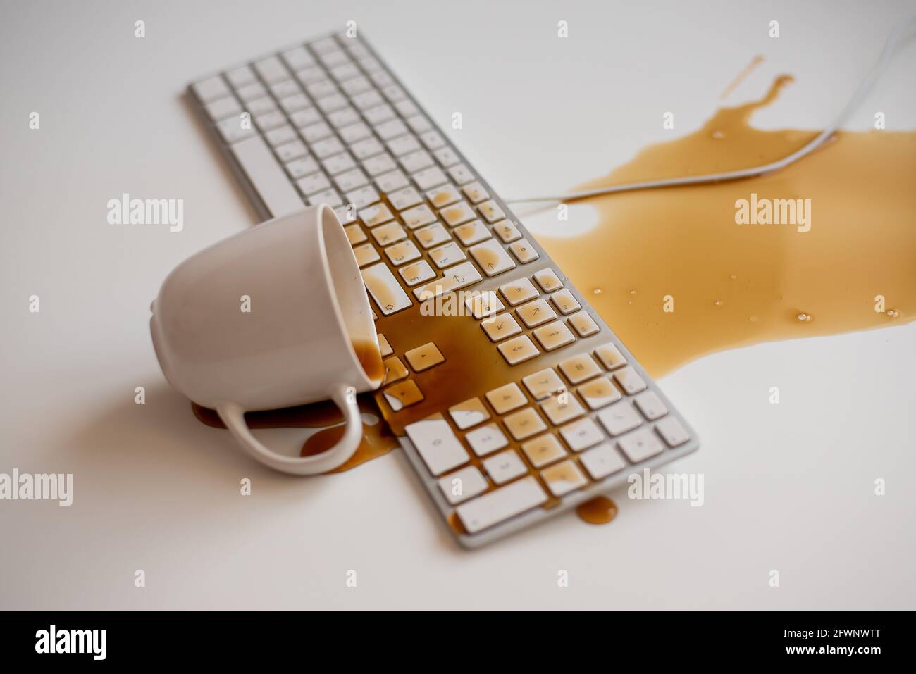 Café noir renversé sur un clavier d'ordinateur à un blanc tableau Banque D'Images Café noir renversé sur un clavier d'ordinateur à un blanc tableau Banque D'Images
