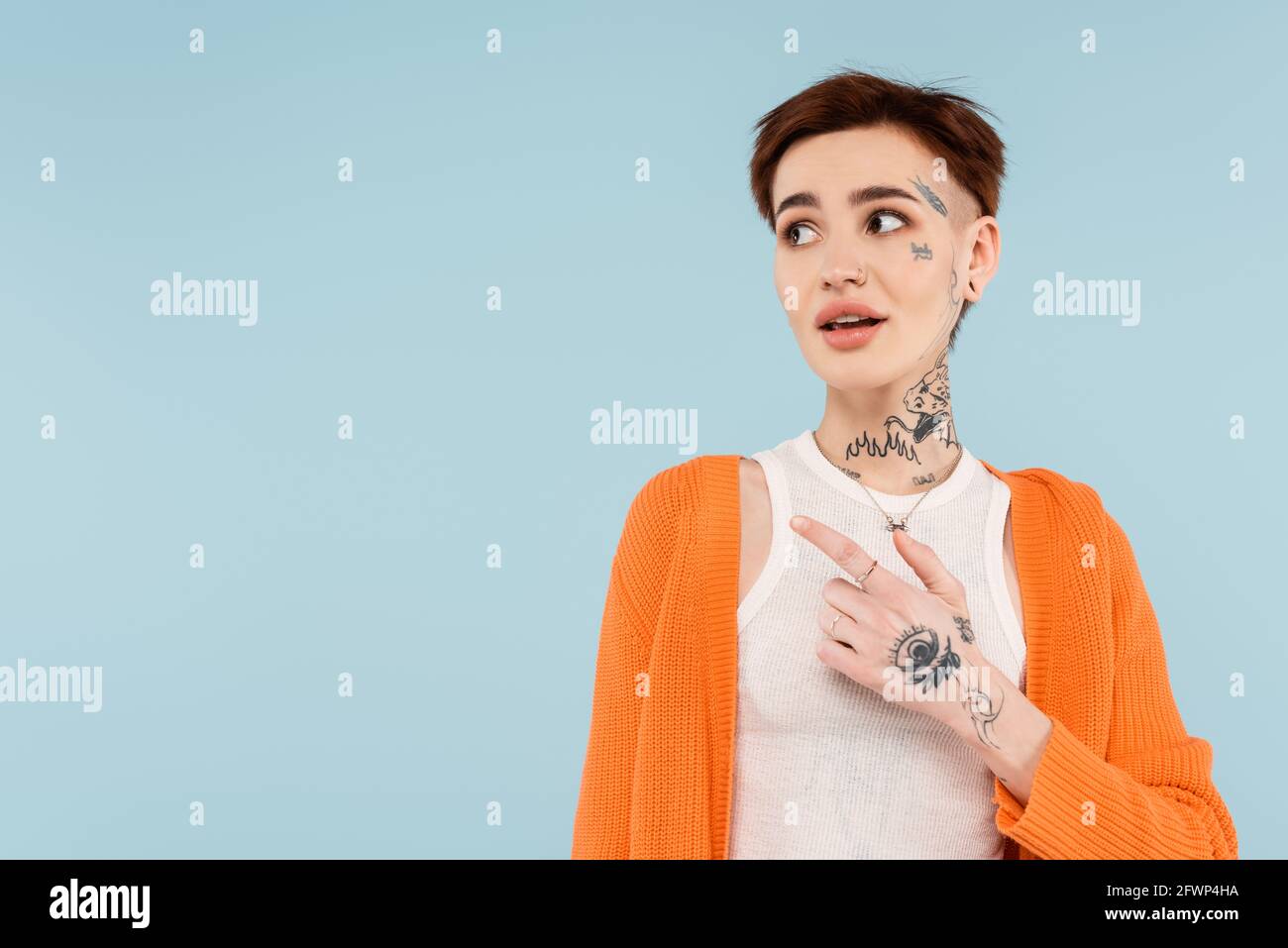 une jeune femme tatouée dans un gilet orange qui le souligne doigt isolé sur bleu Banque D'Images