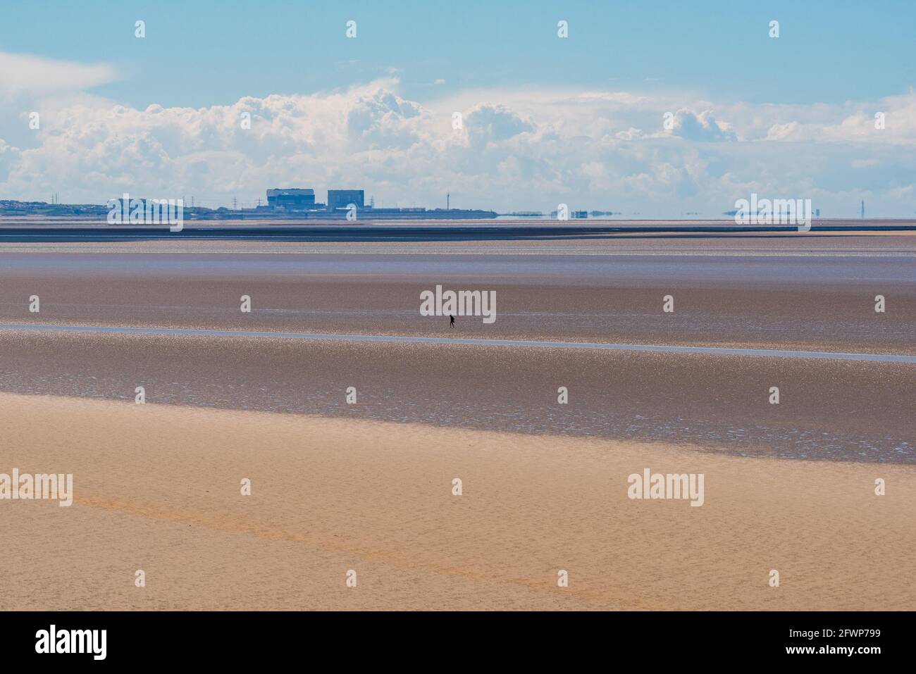 Vue de l'extrême Arnside sur la baie de Morecambe vers la centrale électrique Heysham, Lancashire, Royaume-Uni avec un marcheur sur le sable Banque D'Images