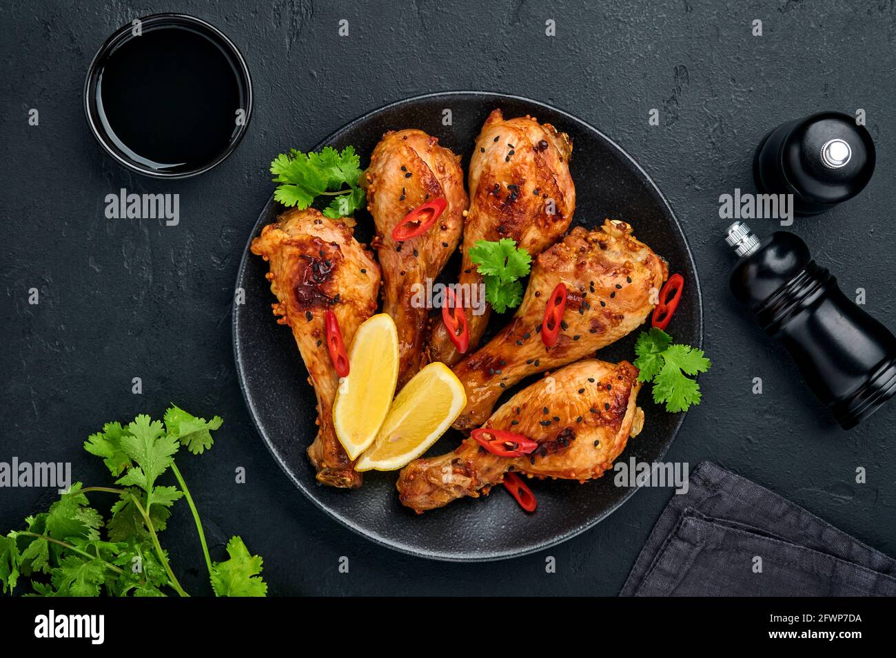 Bâtonnets de poulet grillé ou jambes ou barbecue grillé avec épices et sauce tomate salsa sur une assiette noire. Vue de dessus avec espace de copie. Banque D'Images