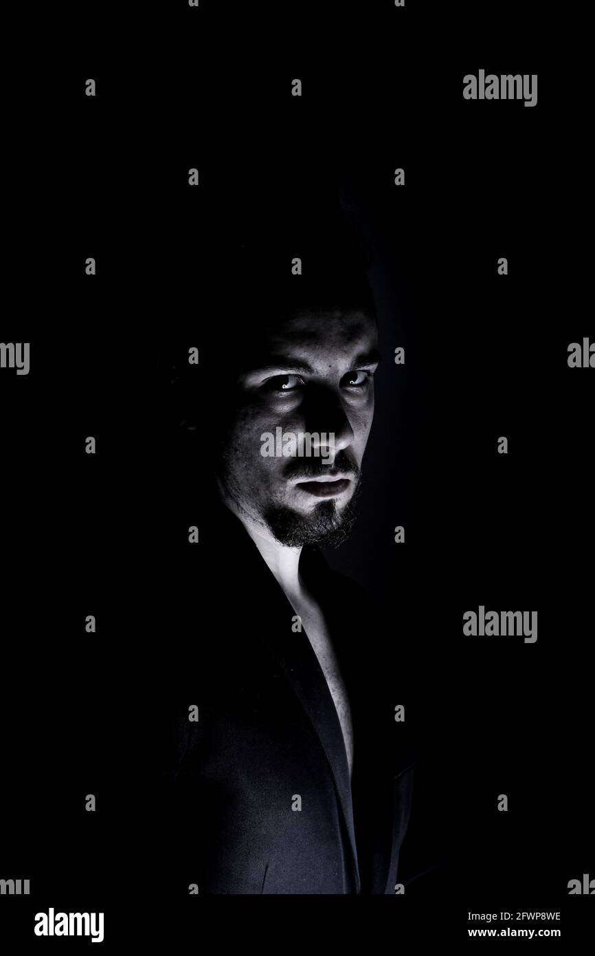 Plan vertical spectaculaire sombre d'un homme avec une expression sérieuse Banque D'Images