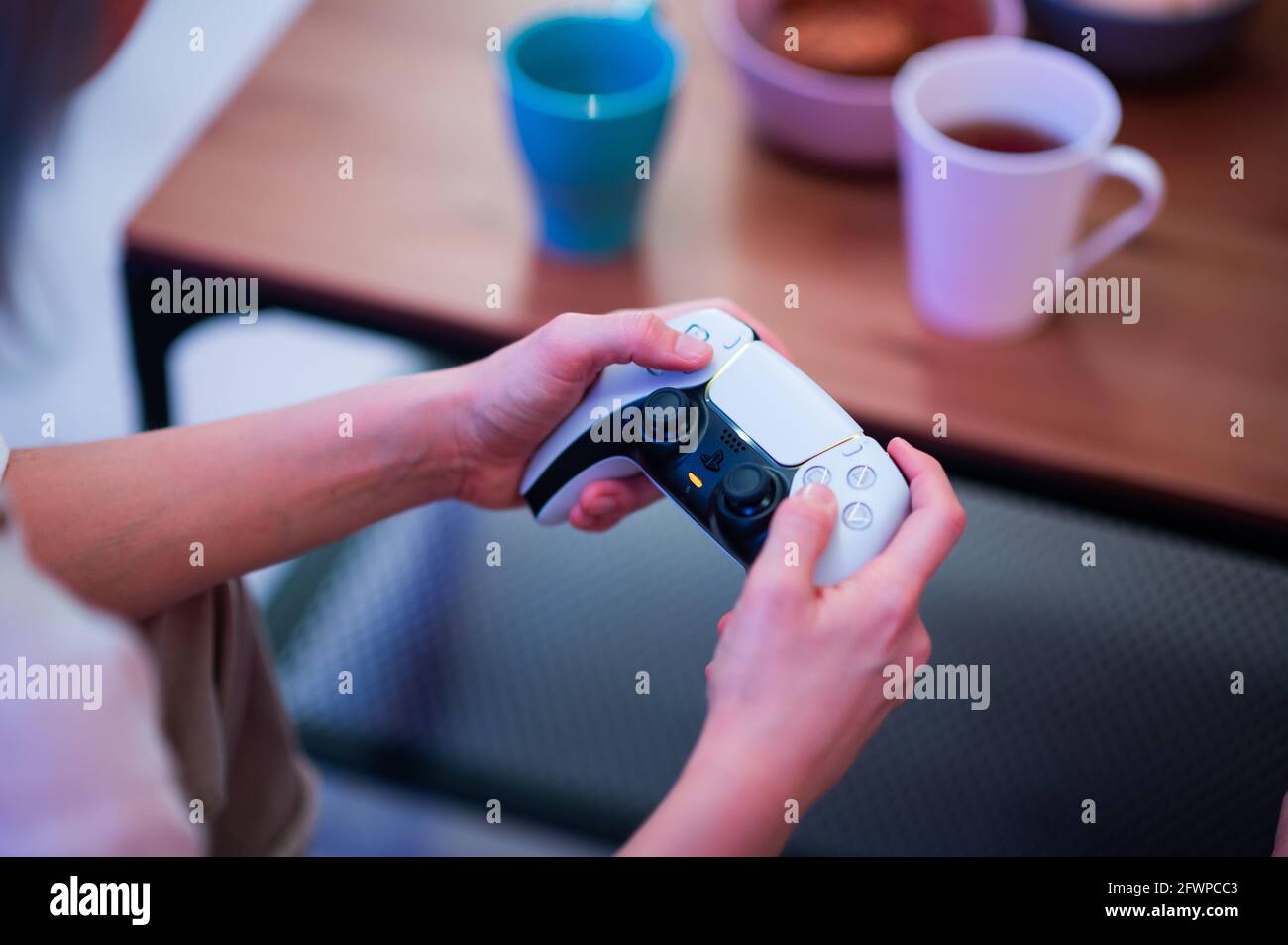 Fille utilisant la nouvelle manette sans fil DualSense PlayStation 5 de Sony qui offre un retour haptique immersif, des déclencheurs dynamiques adaptatifs et un micro intégré Banque D'Images