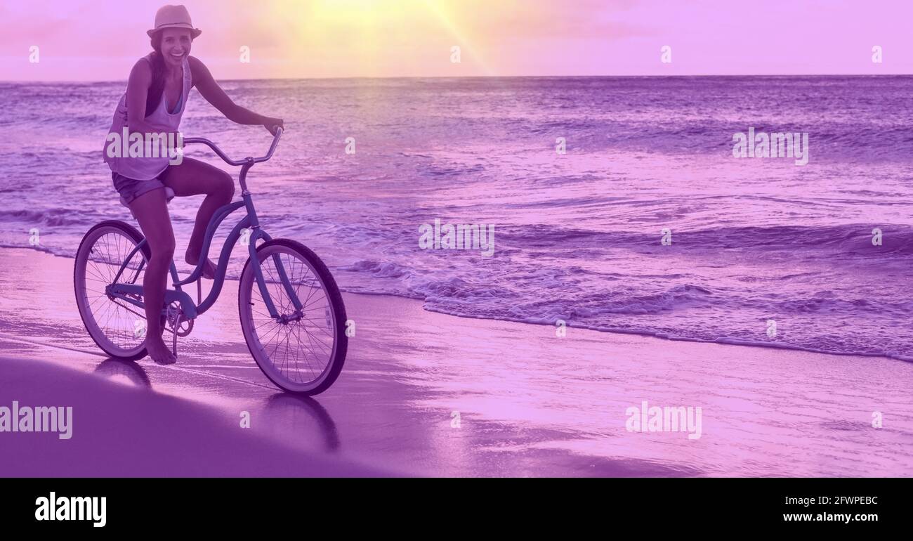 Composition d'homme souriant à vélo sur la plage par mer avec teinte pourpre Banque D'Images