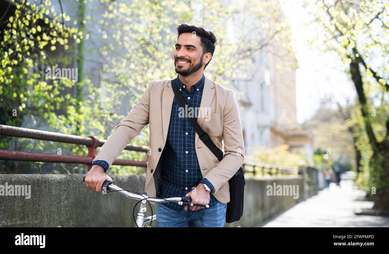 Un jeune homme d'affaires se déplaça avec un vélo qui va travailler à l'extérieur en ville. Banque D'Images