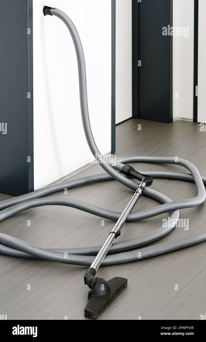 Long tuyau central pour aspirateur posé sur le sol gris de la pièce.  Flexible de l'aspirateur central branché dans une prise murale Photo Stock  - Alamy