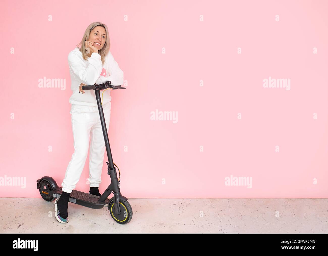 Blonde souriante femme heureuse d'acheter un scooter électrique, modes alternatifs de transport concept Banque D'Images