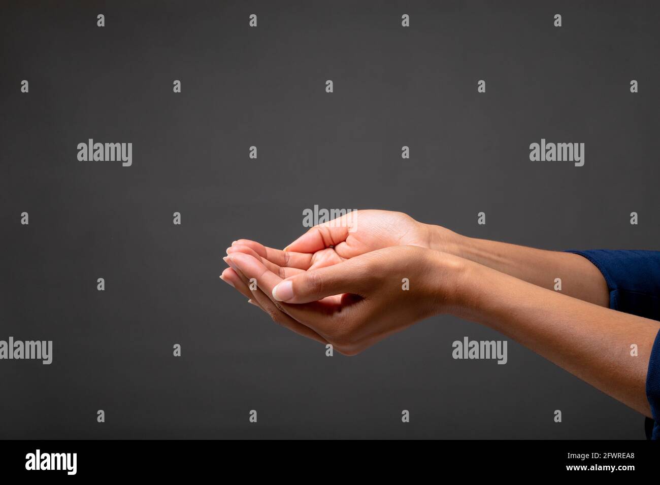 Gros plan d'une femme d'affaires avec ses mains en coupe sur fond gris Banque D'Images