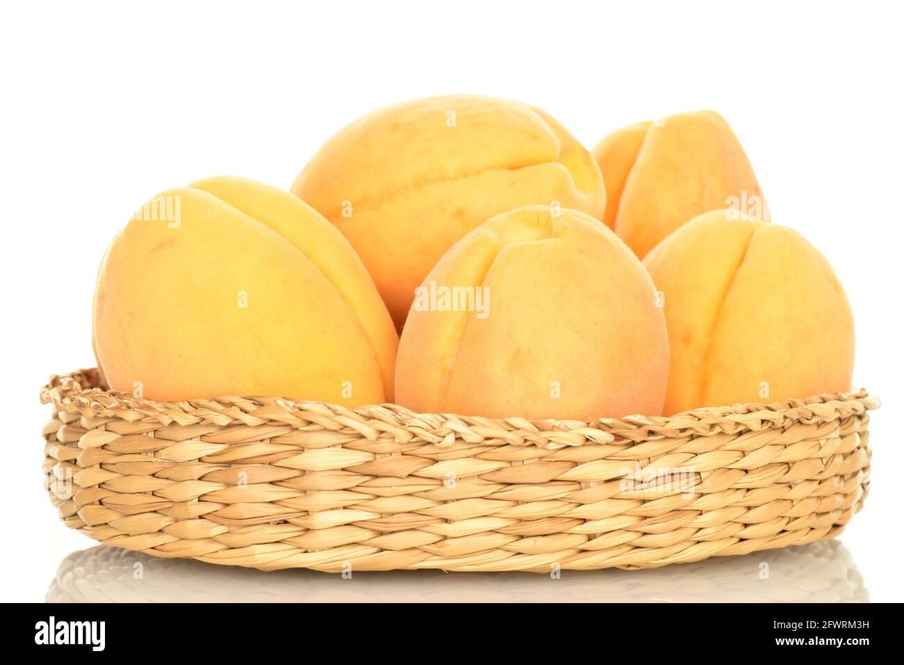 Plusieurs abricots mûrs d'ananas dans une plaque de paille, en gros plan, isolés sur du blanc. Banque D'Images