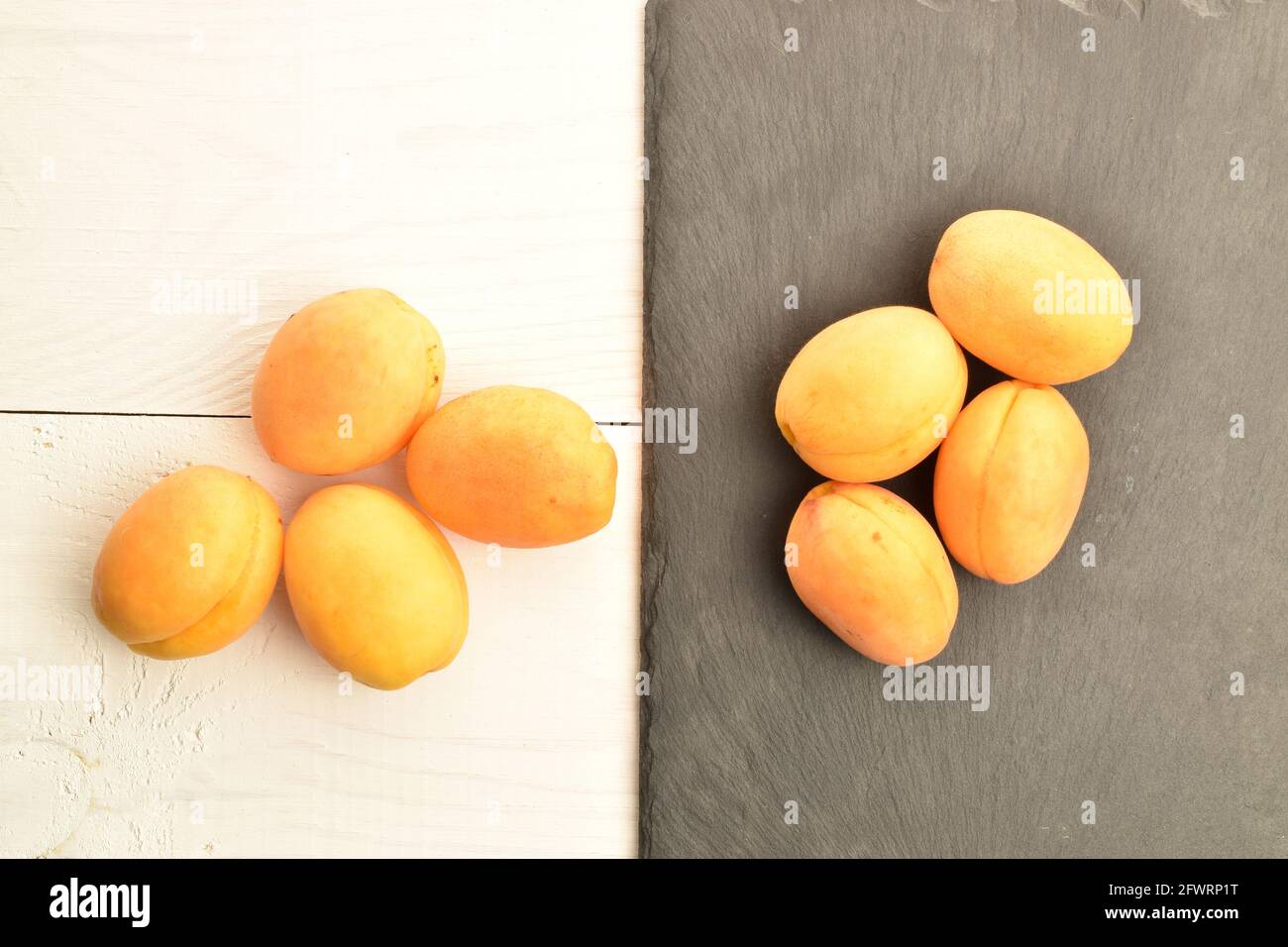 Plusieurs abricots mûrs d'ananas jaune, gros plan, sur un tableau d'ardoise et une table en bois blanc, vue du dessus. Banque D'Images