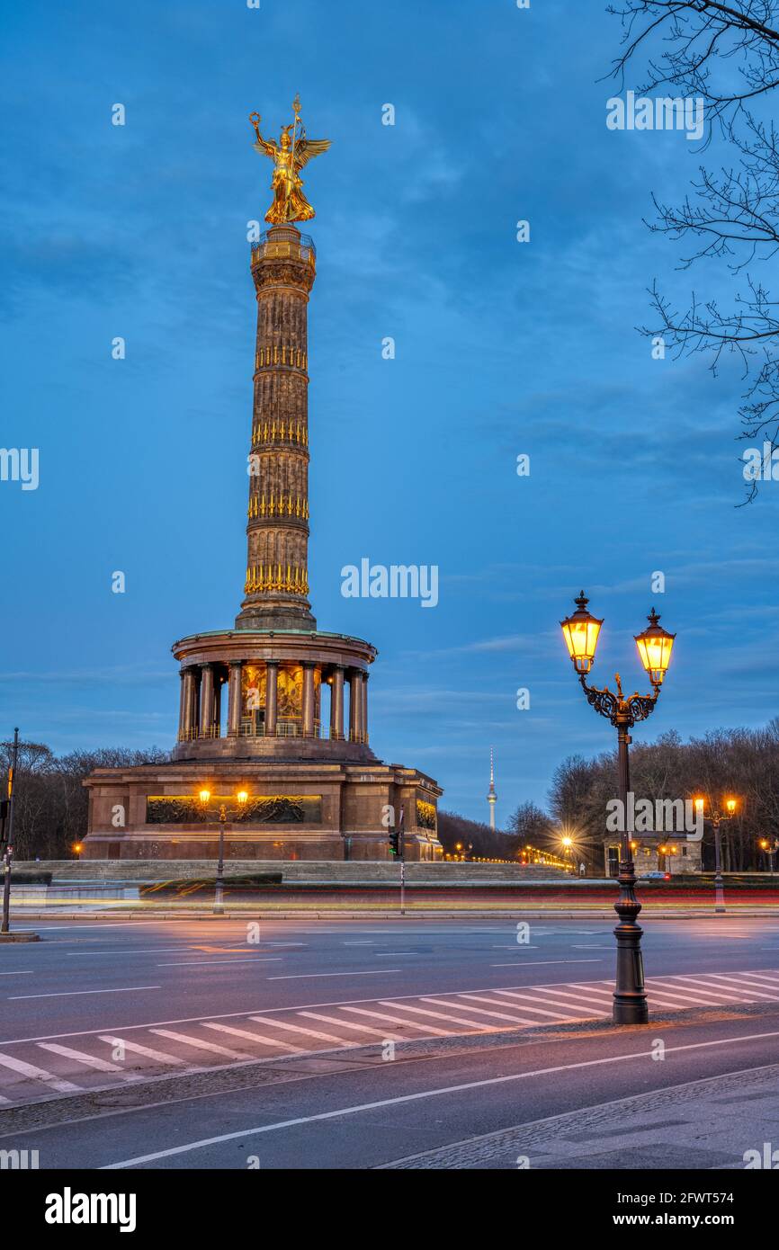 La célèbre colonne de la victoire avec une lumière de rue et des branches d'arbre à Berlin, en Allemagne, au crépuscule Banque D'Images