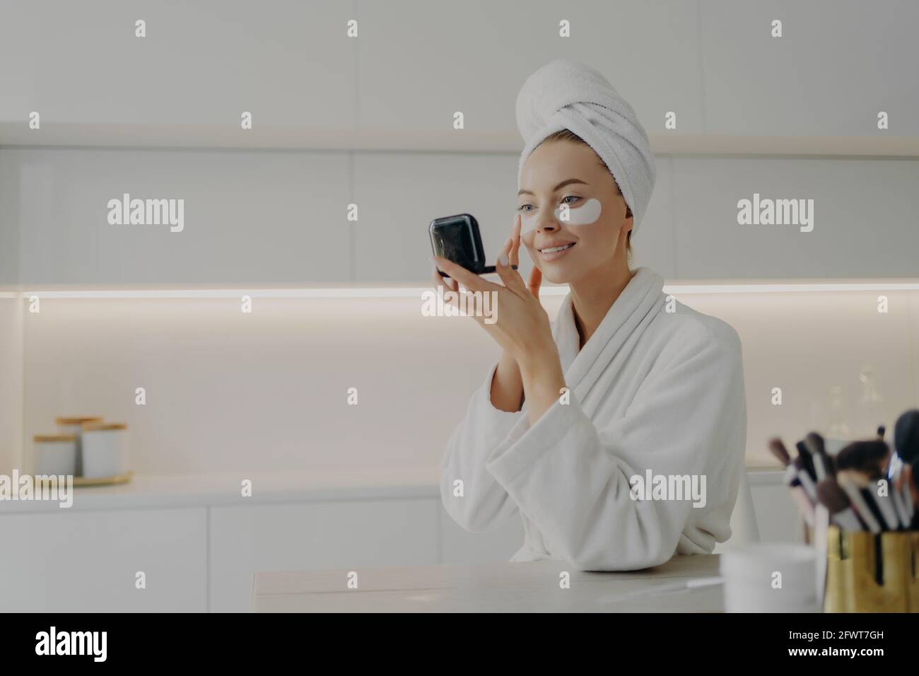 Femme heureuse avec peignoir blanc et serviette sur la tête soin de sa peau après la douche du matin Banque D'Images