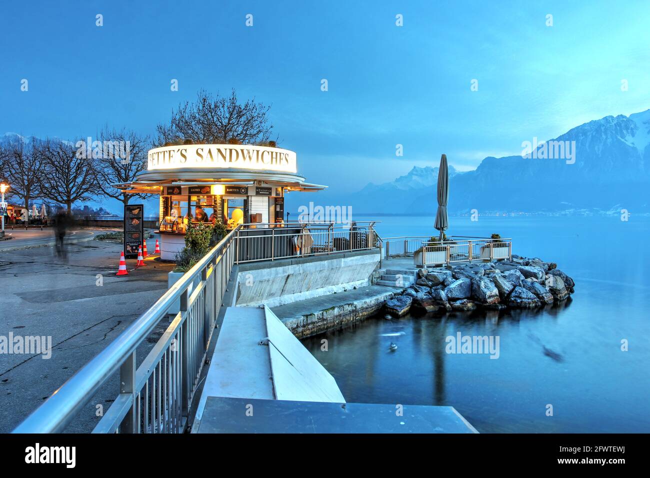 Soirée d'hiver le long de la promenade au bord de l'eau à Vevey, Suisse, avec une boutique art déco, des sandwiches Babette servant des sucreries au visito Banque D'Images