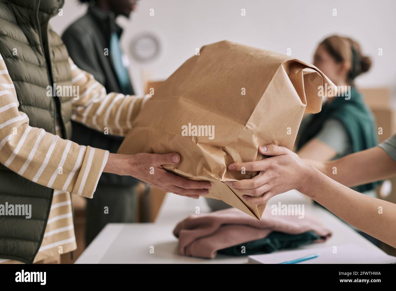 Gros plan d'une personne méconnue qui donne un sac en papier aux bénévoles pendant l'événement d'aide et de dons, espace de copie Banque D'Images