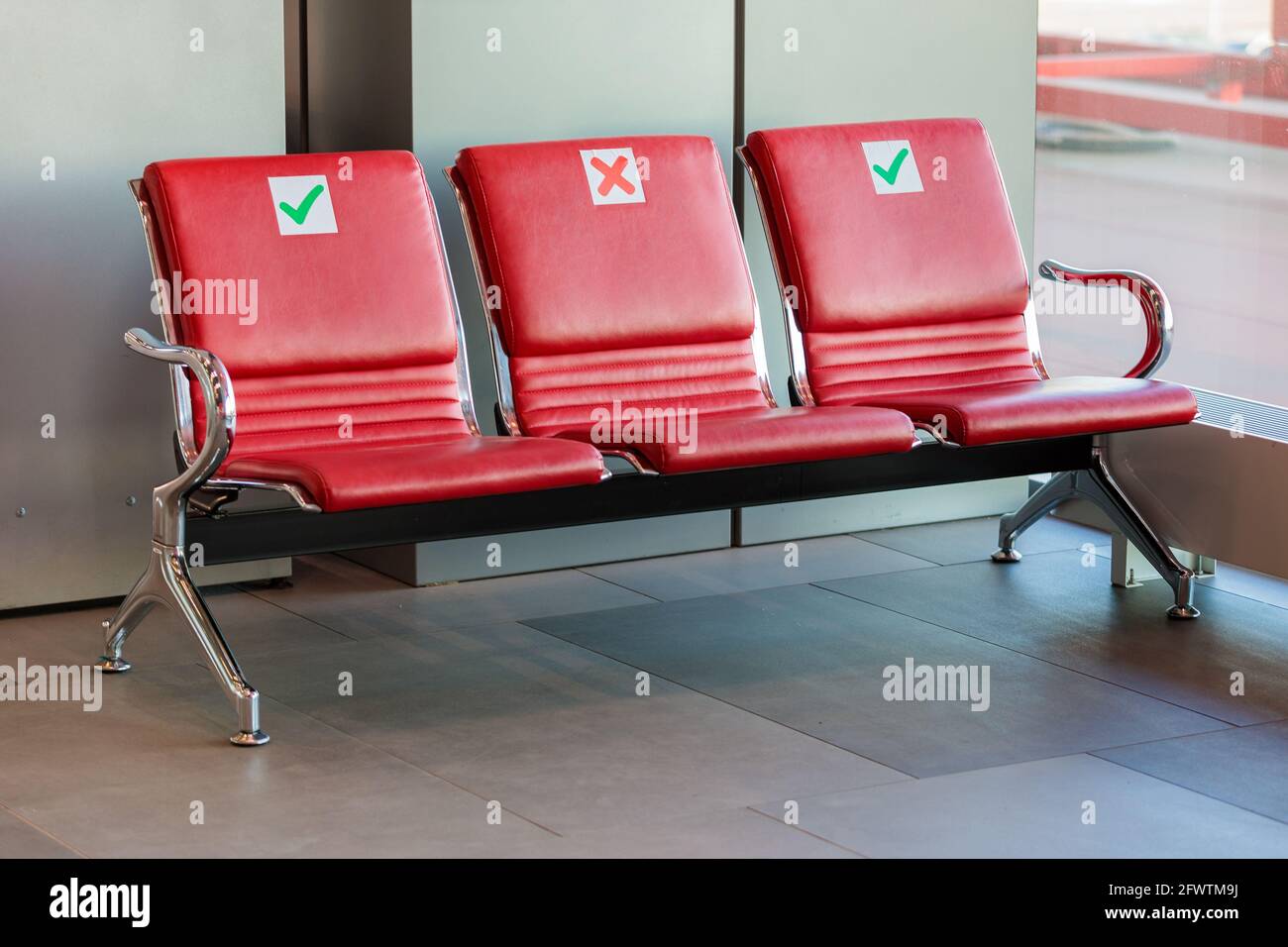 Signes sociaux de distanciation sur les chaises de COVID-19. Bâtiment de l'aéroport, hall des départs. Banque D'Images