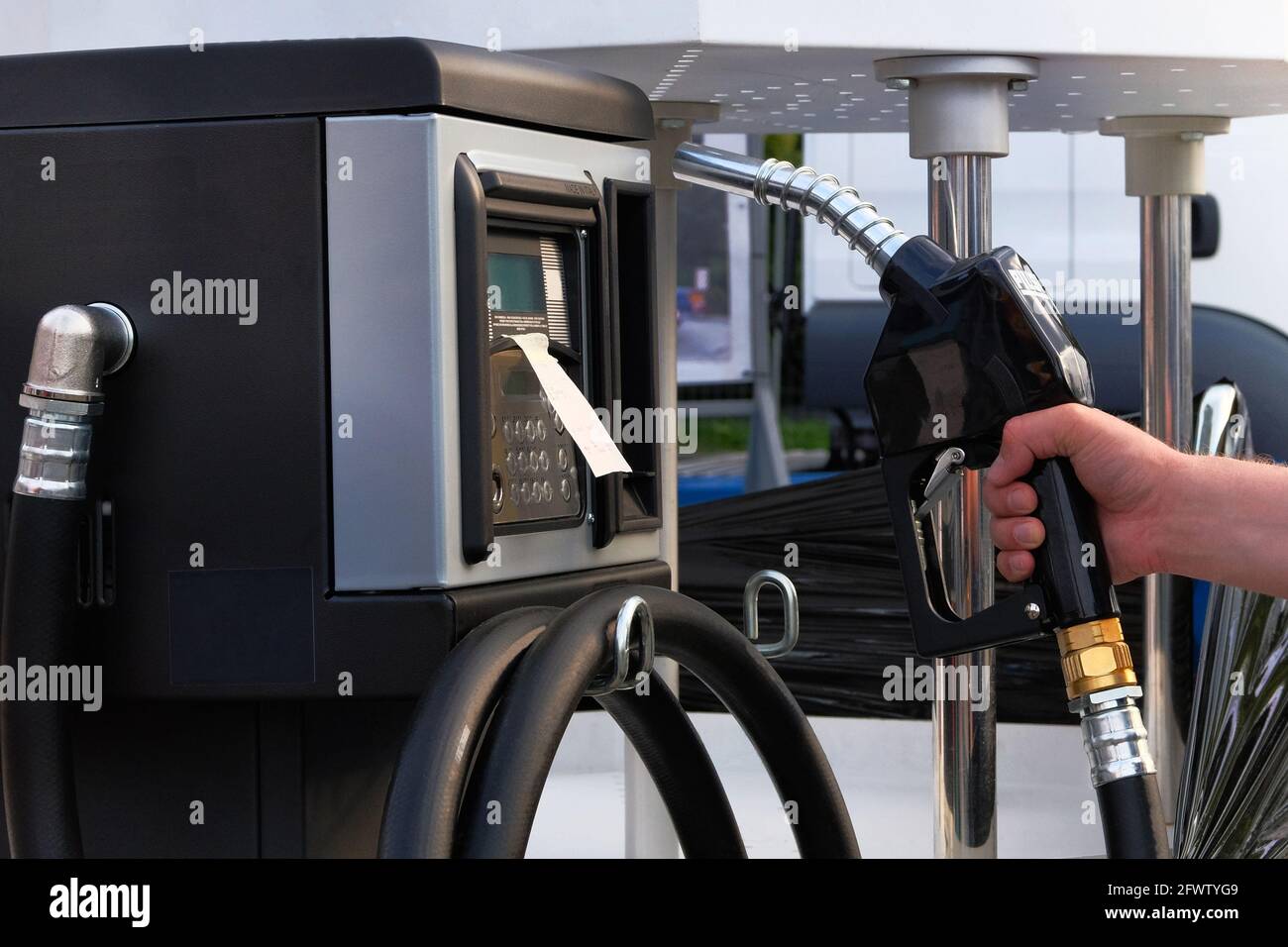 Main d'un homme tenant la pompe à essence en se protégeant d'un papier,  pour remplir le réservoir de sa voiture avec du diesel Stock Photo