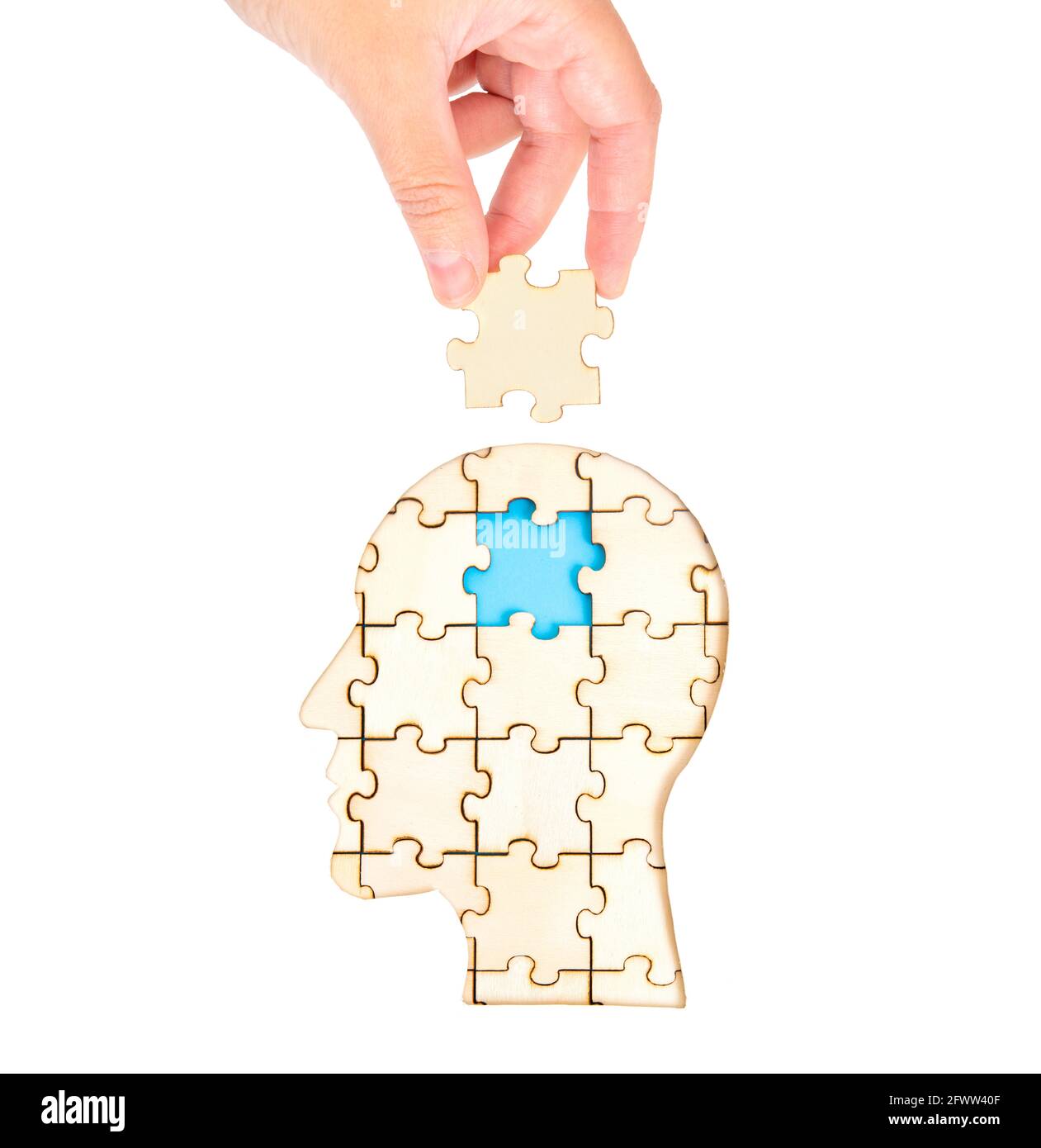 Main femelle plaçant la pièce manquante du cerveau du puzzle formant une tête humaine isolée sur blanc. Concept de traitement mental et de thérapie. Banque D'Images