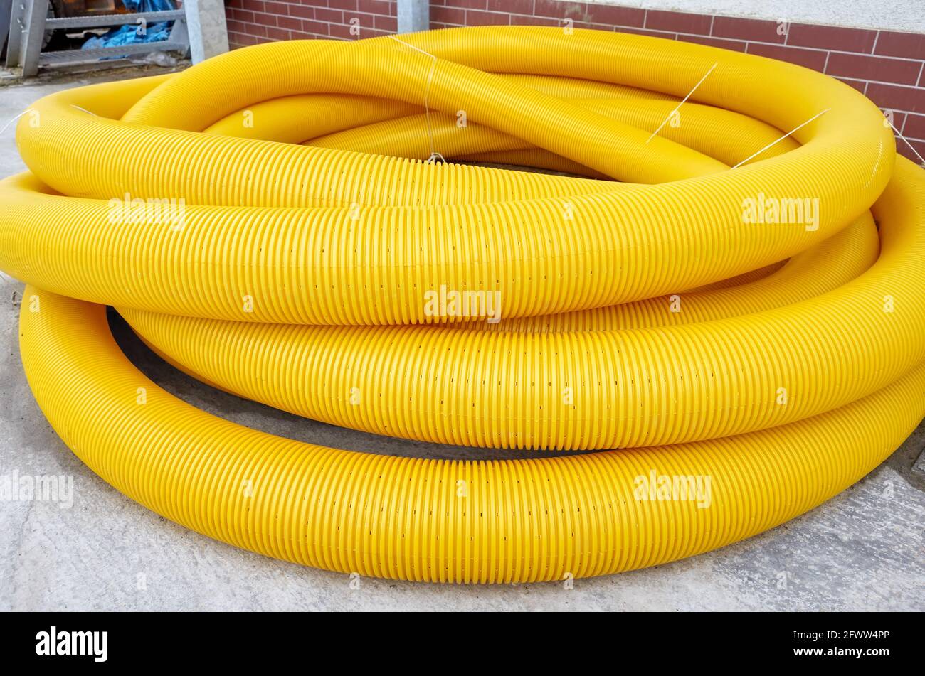 Tuyau de drainage de terre de bobine jaune sur le sol, il est utilisé pour enlever l'eau excessive des champs et des jardins. Banque D'Images