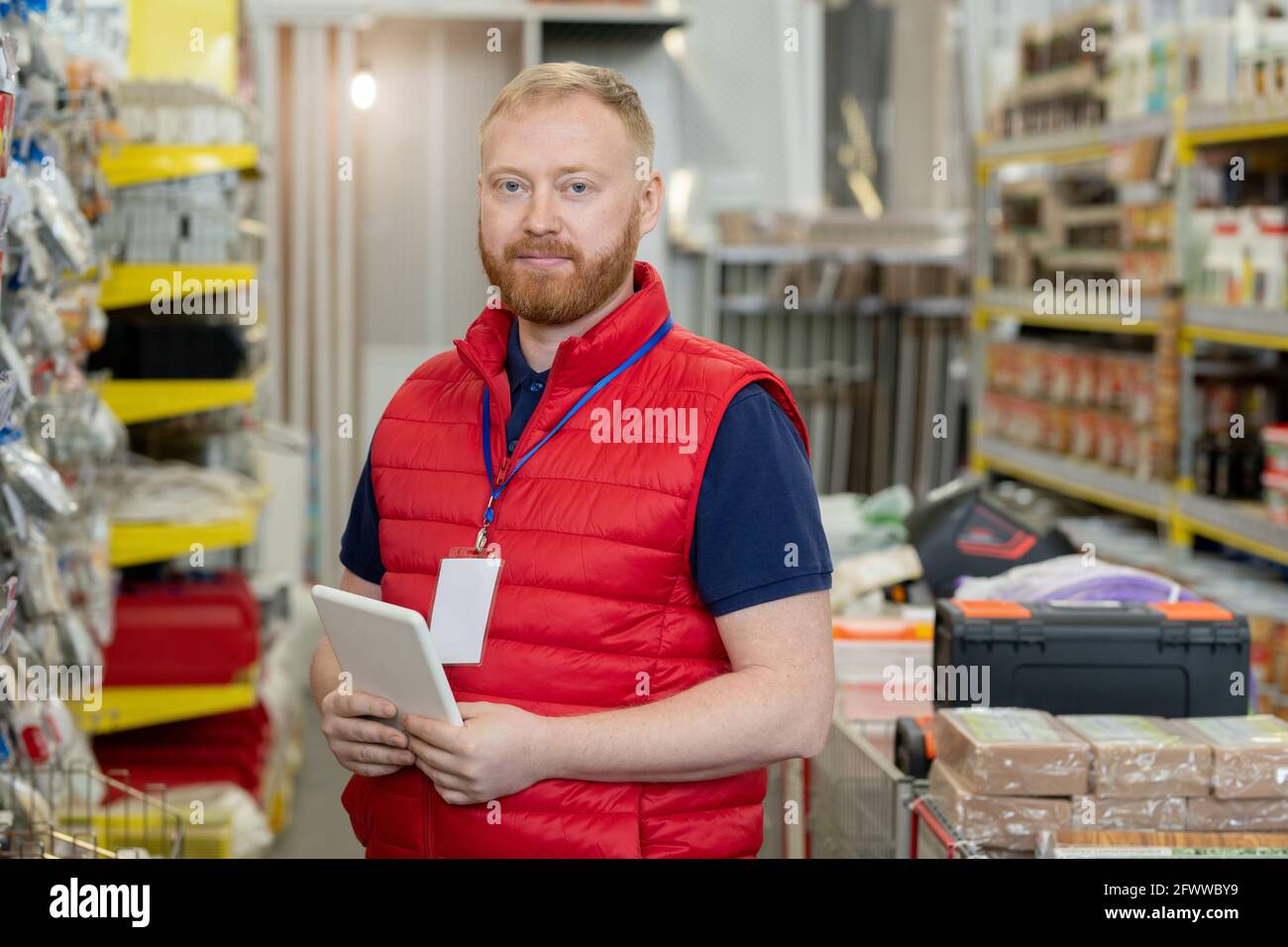 Jeune homme assistant de magasin réussi en uniforme Banque D'Images