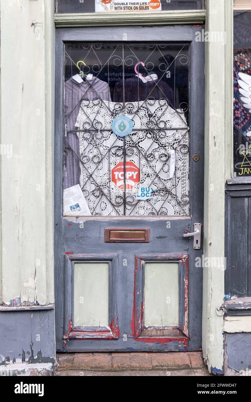 Porte de magasin fermée avec peinture décolorée et vêtements dans la fenêtre, Abergavenny, pays de Galles, Royaume-Uni Banque D'Images