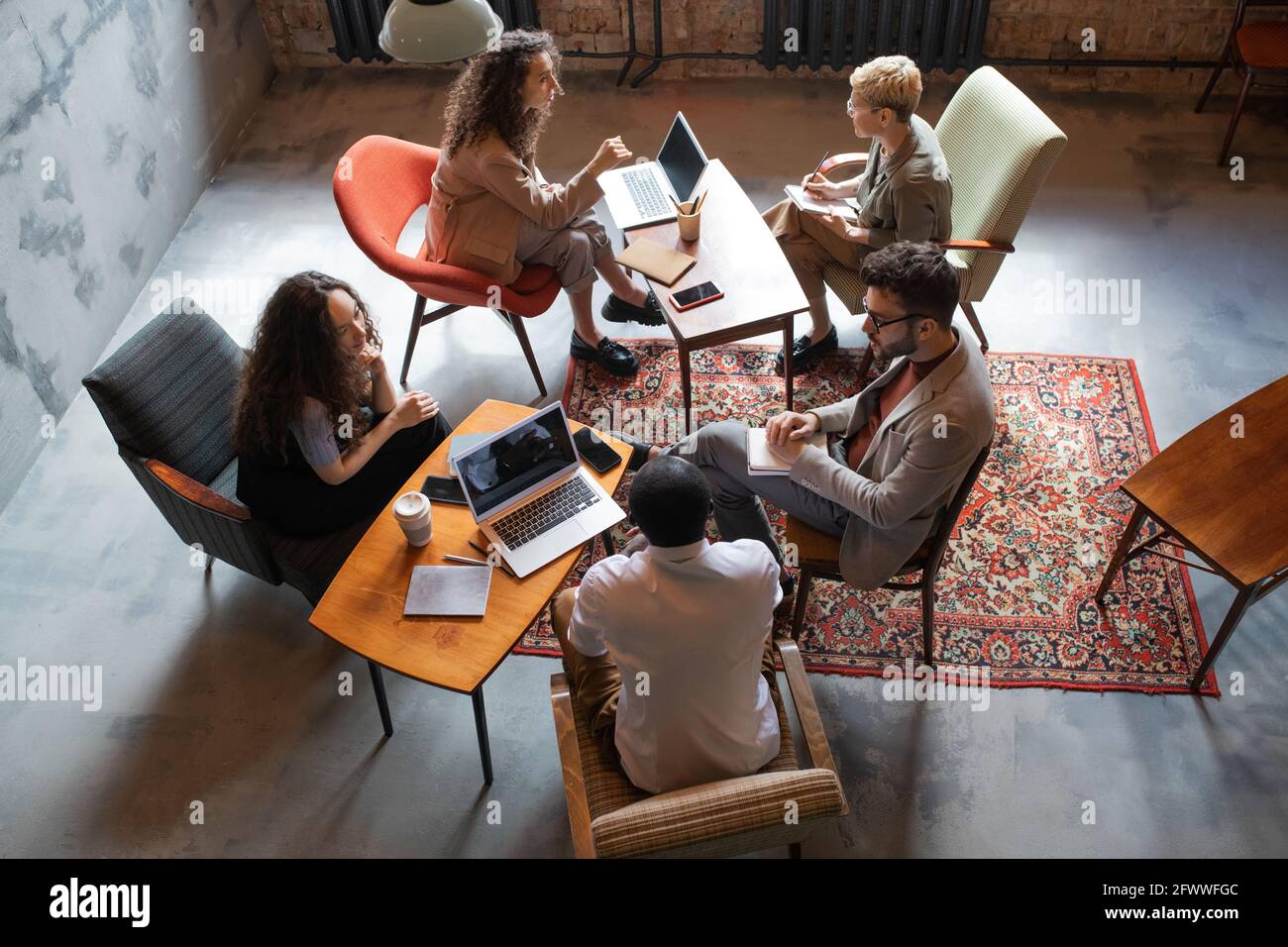 Plusieurs gens d'affaires interculturels interagissant par des tables au bureau Banque D'Images