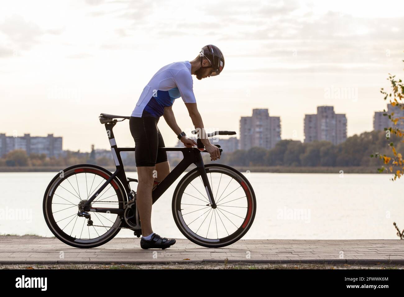 Jeune sportif sur l'entraînement à vélo dans le parc contre le ciel nuageux ciel Banque D'Images