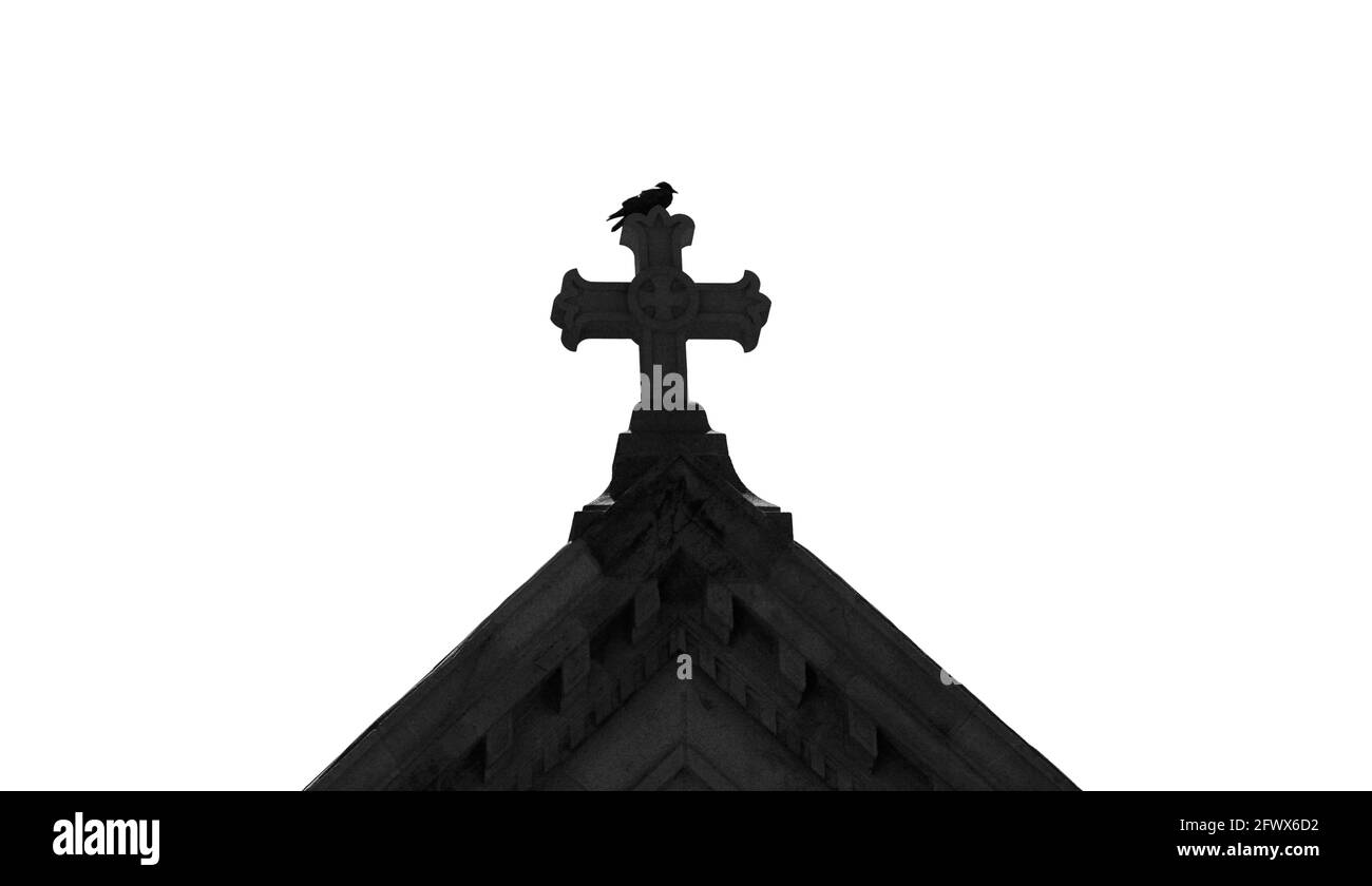 Un oiseau perche au-dessus d'une croix de pierre sur le dessus de la basilique historique de la cathédrale Saint François d'Assise à Santa Fe, Nouveau-Mexique. Banque D'Images