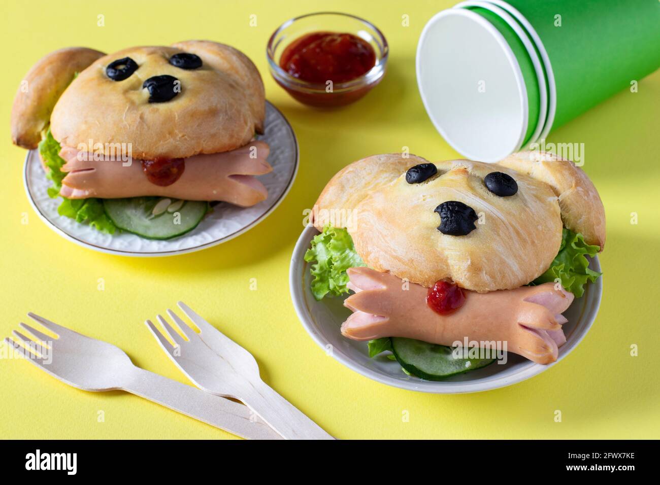 Sandwichs en forme de chien avec saucisse sur fond jaune. Idée de cuisine pour les enfants. Gros plan Banque D'Images