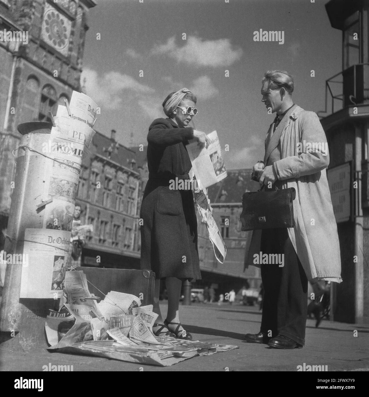 Amsterdam. Un vendeur de journaux devant la gare centrale avec un client, 18 juin 1946, commerce, journaux, Places, stations, vendeurs de rue, femmes, pays-Bas, agence de presse du xxe siècle photo, nouvelles à retenir, documentaire, photographie historique 1945-1990, histoires visuelles, L'histoire humaine du XXe siècle, immortaliser des moments dans le temps Banque D'Images