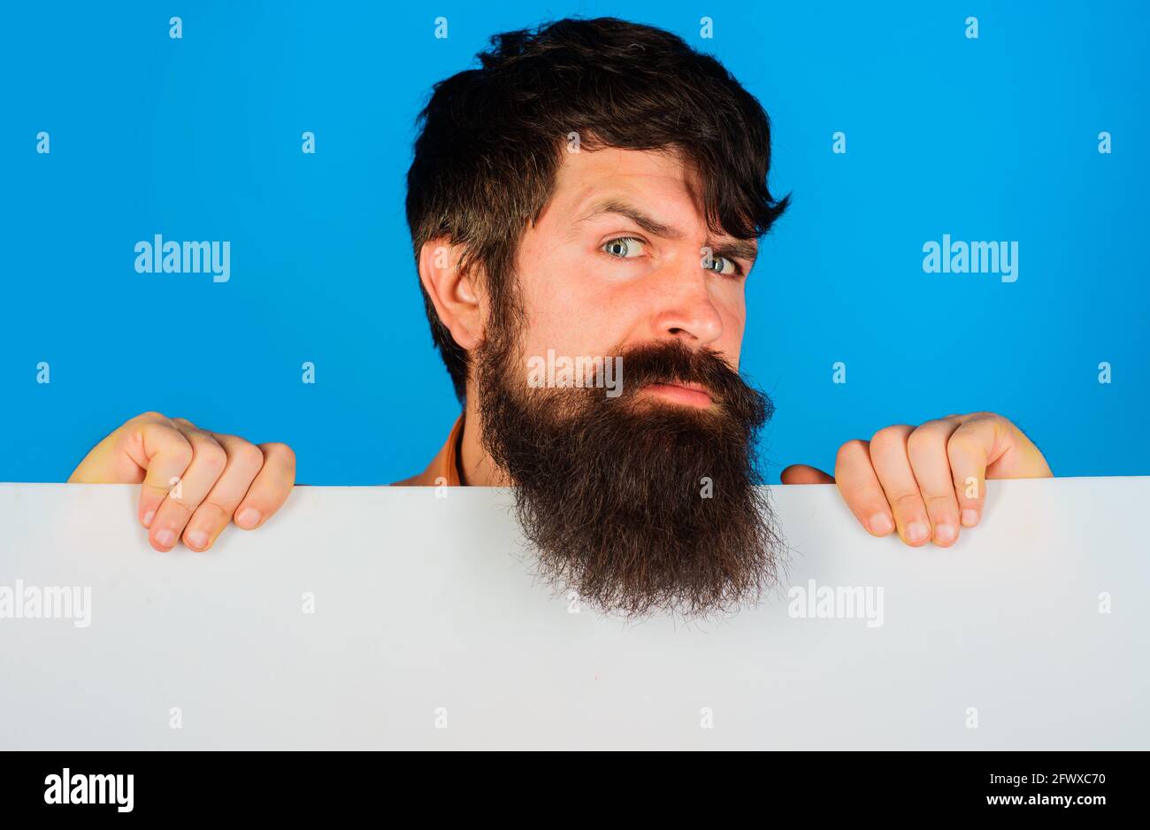 Homme barbu avec tableau vierge avec espace pour le texte. Homme sérieux avec bannière publicitaire. Banque D'Images