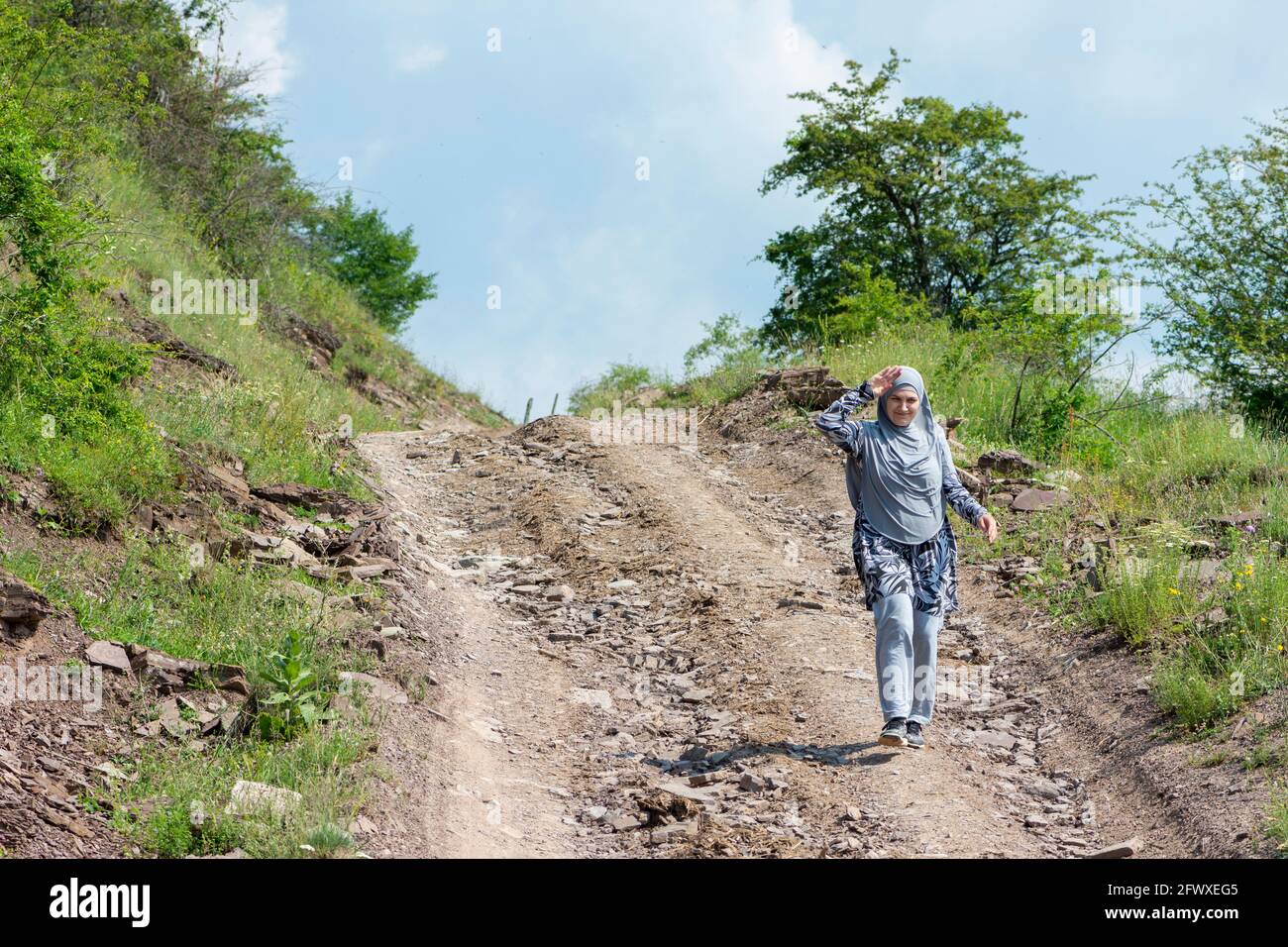 Jeune fille musulmane portant des vêtements de sport marchant seule sur le route rurale de montagne Banque D'Images