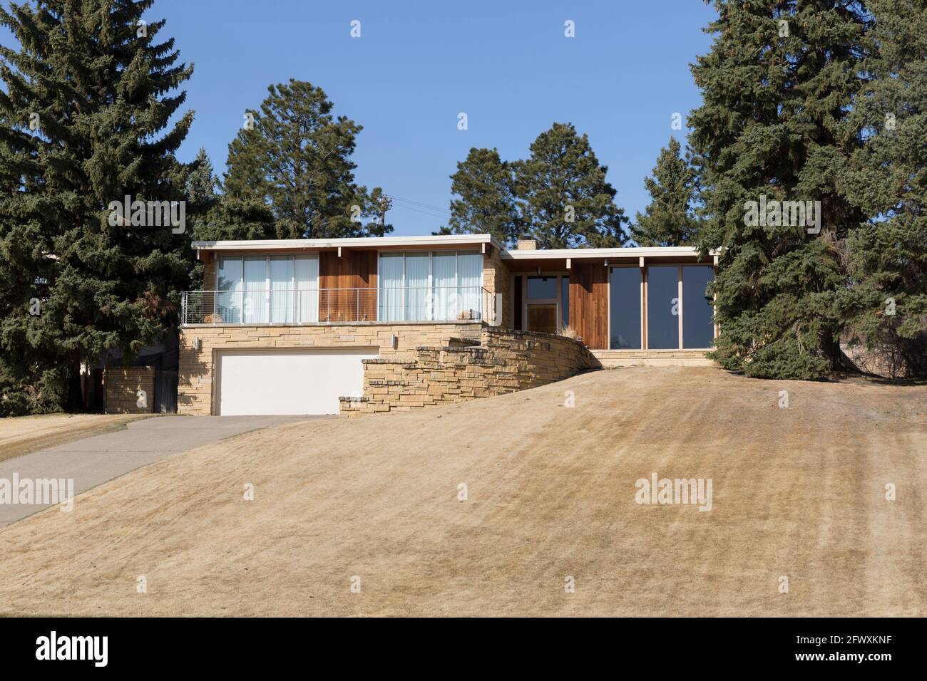 Architecture montrant l'extérieur d'une maison moderne de style ranch MCM du milieu du siècle avec une pelouse avant dormante brune. Banque D'Images