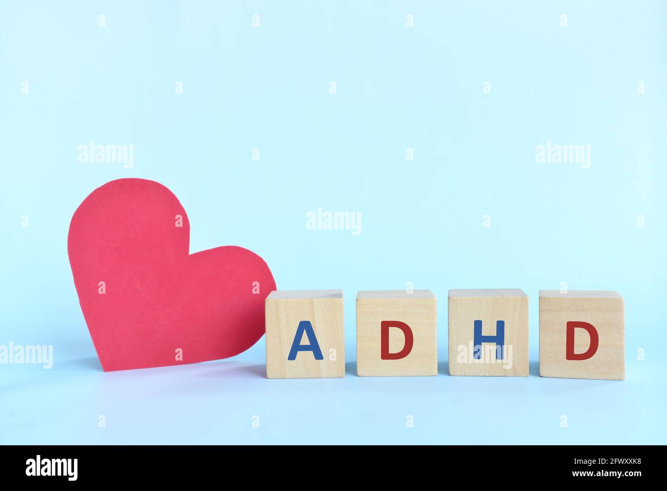 Aimer et soutenir les enfants atteints de TDAH ou de trouble d'hyperactivité avec déficit de l'attention. Lettres de TDAH sur des blocs de bois à côté d'une forme de coeur rouge Banque D'Images