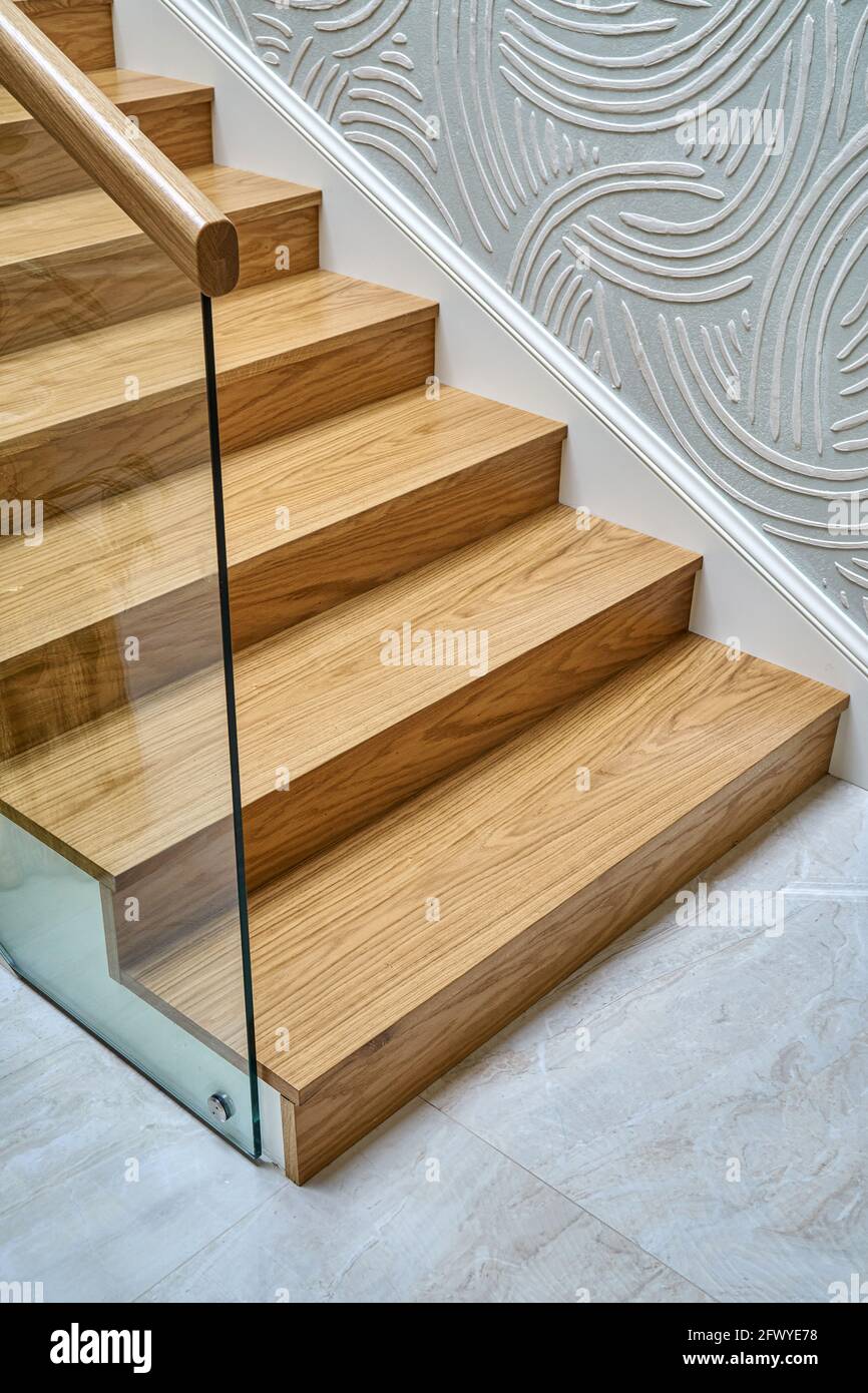 Escalier en bois avec garde-corps en verre et main courante en bois de solide chêne vue rapprochée Banque D'Images