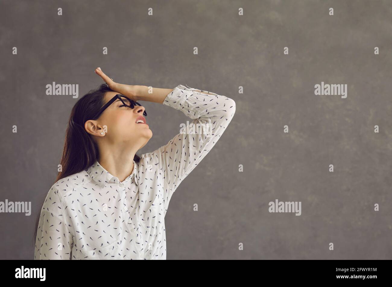 La jeune femme caucasienne touchant le front regrette de ne pas avoir fait une photo en studio Banque D'Images