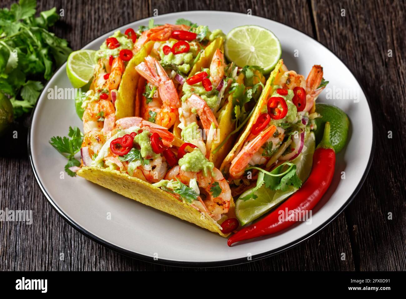 coquilles à tacos avec crevettes grillées, salade de chou, citron vert et guacamole sur une assiette Banque D'Images