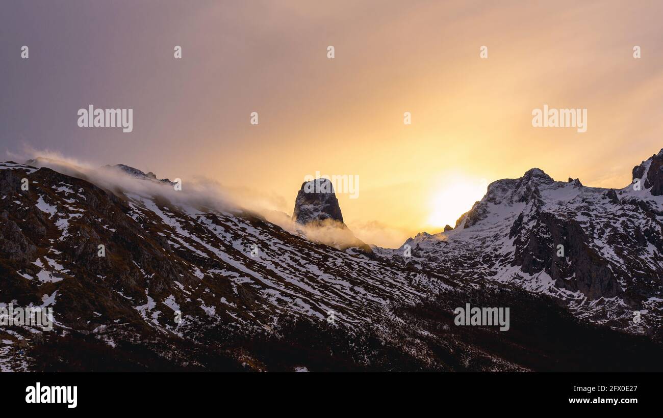 Paysage grand angle des sommets de l'Europe avec la neige et brouillard sous les nuages pendant le coucher du soleil Banque D'Images