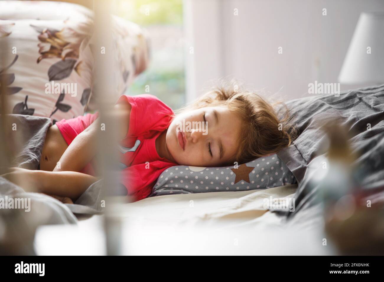 Un petit enfant dort doucement dans son lit. Sommeil sain de la fille, ventilation. Matin, réveil, lumière du soleil de la fenêtre. Ascension précoce vers un jardin d'enfants Banque D'Images