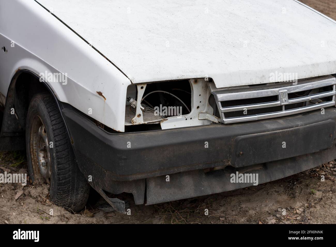 La voiture est abandonnée sans phare. Journée en ville, vue de face horizontale. Banque D'Images