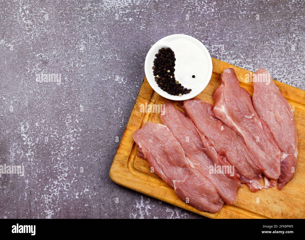Côtelette de jambe brute de la jambe de porc sur une planche de bois sur un fond en bois foncé. Vue de dessus, plan d'appartement Banque D'Images